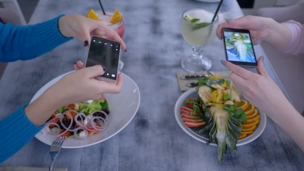 fresh party, female Friends используют современные мобильные технологии и фотографируют красивую еду для социальных сетей во время здорового ужина в кафе
 - Кадры, видео