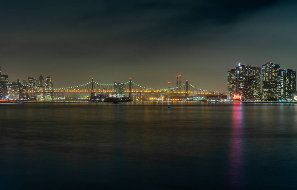 NOVA IORQUE, ESTADOS UNIDOS - JANEIRO 9, 2019: Vista da Ponte Ed Koch Queensboro e do Parque Estadual Gantry Plaza da ribeira do Rio East à noite
 - Foto, Imagem