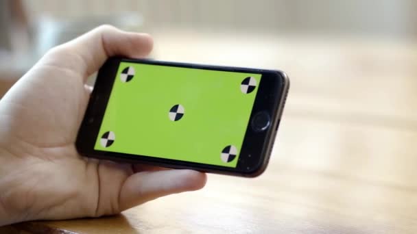 Крупним планом рука тримає телефон горизонтально з зеленим екраном. Стокові кадри. Людина тримає телефон горизонтально однією рукою для перегляду відео або фільмів
 - Кадри, відео