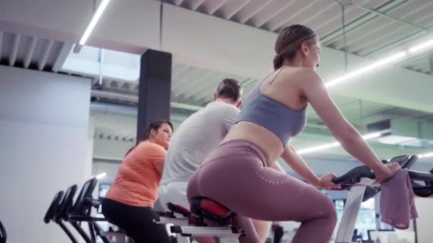 Чоловік і жінки крутяться на фітнес-велосипедах в тренажерному залі
 - Кадри, відео