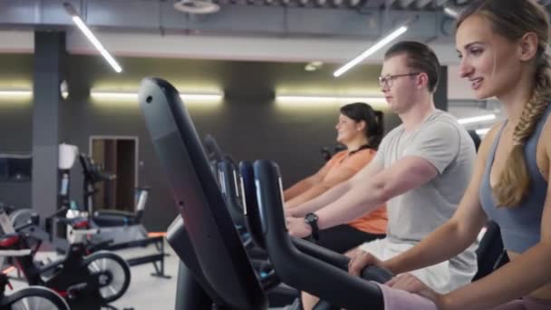A fitnesskerékpáron lévő emberek oktatóval - Felvétel, videó