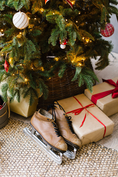 Vieux patins bruns se trouvent sous le sapin de Noël avec des cadeaux
 - Photo, image