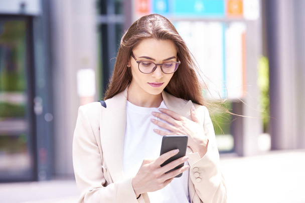Close-up shot of young businesswoman standing on the street and text messaging.  - Foto, Bild