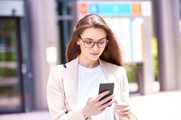 Close-up shot of young businesswoman standing on the street and text messaging.  - Foto, imagen