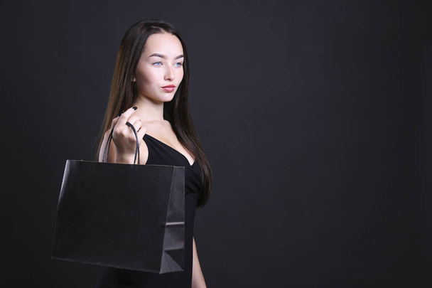 Young woman dressed in all black posing with shopping bag. - Foto, Imagem