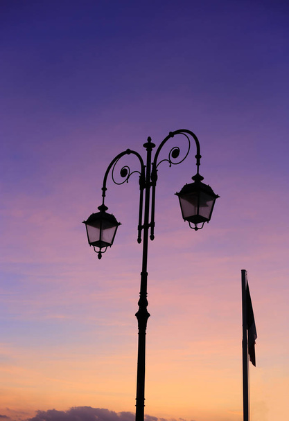 Красивая винтажная уличная лампа против яркого неба восхода солнца
 - Фото, изображение