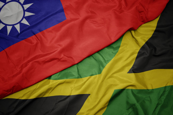machając barwną flagą Jamajki i narodową flagą Tajwanu. - Zdjęcie, obraz