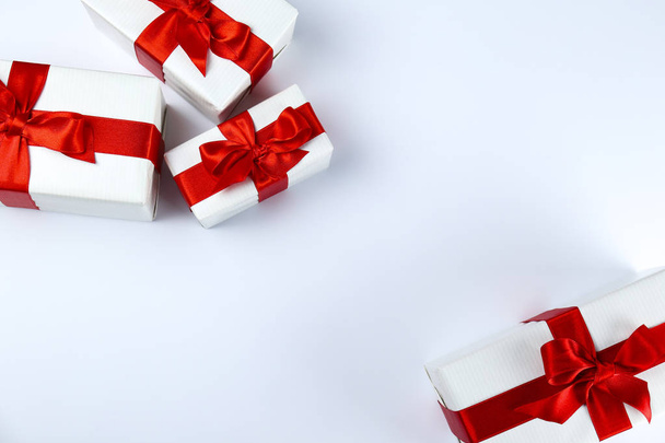 Ramo de regalos de Navidad envueltos en papel rojo y blanco atado con lazo de seda brillante. Múltiples regalos de año nuevo en envoltura roja y blanca. Vista superior, primer plano, espacio para copiar, fondo, plano
. - Foto, Imagen