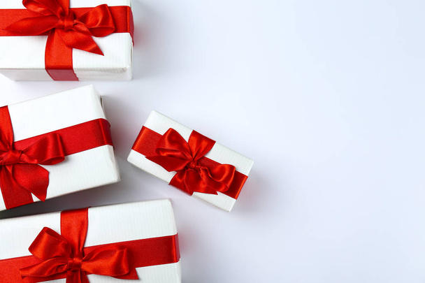 Bunch of christmas presents wrapped in red and white paper tied with shiny silk bow. Multiple new years gifts in red and white wrapping. Top view, close up, copy space, background, flat lay. - Foto, Imagen
