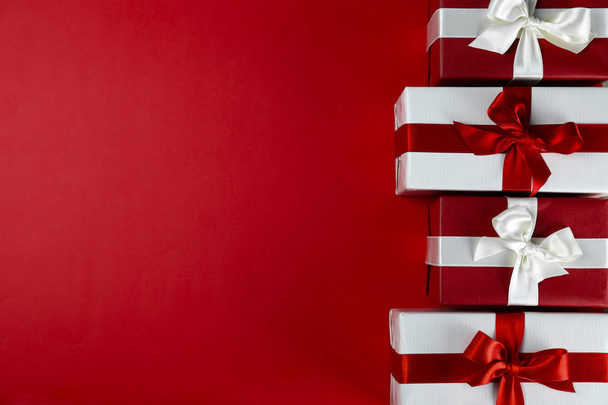 Ramo de regalos de Navidad envueltos en papel rojo y blanco atado con lazo de seda brillante. Múltiples regalos de año nuevo en envoltura roja y blanca. Vista superior, primer plano, espacio para copiar, fondo, plano
. - Foto, imagen