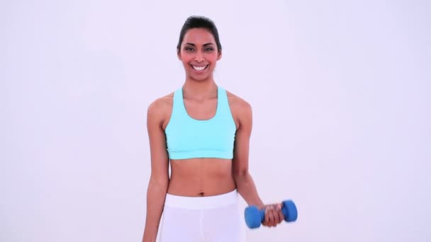 Fit woman lifting hand weights and smiling at camera - Πλάνα, βίντεο