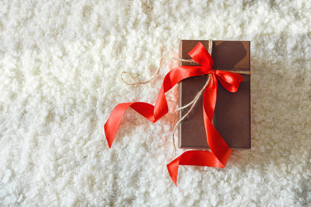 Beautiful gift box with red ribbon. Box for a gift. White cozy plaid. New year, Christmas. On the eve of the holiday. - Foto, imagen
