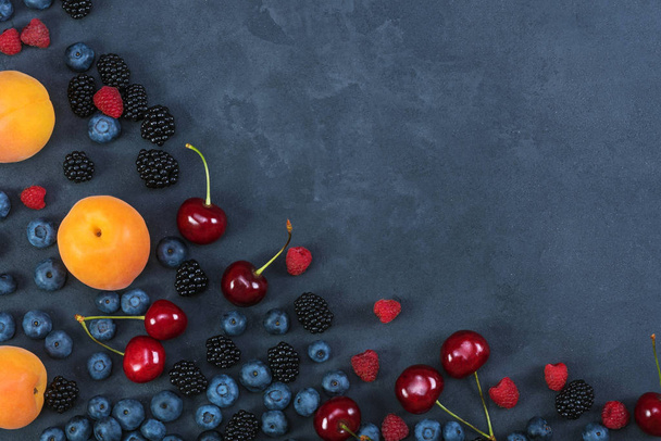 Blackberries,blueberries,raspberries,cherries on black concrete background. Healthy food - Фото, зображення