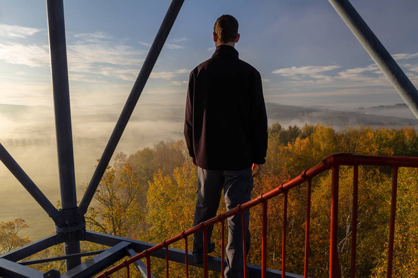 Молодой человек, стоящий на строительстве сторожевой башни, смотрит на осень
  - Фото, изображение