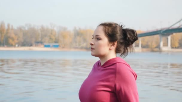 Close up view of attractive female walking with nordic poles along city river and park. Outdoor recreation concept - Filmati, video