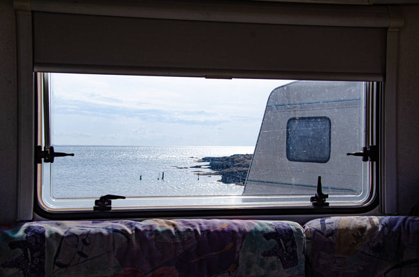 海のそばのトレーラーで休んでください。海沿いの旅行。モーターホームの窓から海への眺め. - 写真・画像