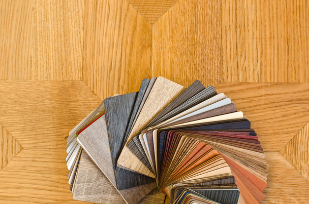Different color samples of wood floor on brown parquet background. - Foto, Imagem