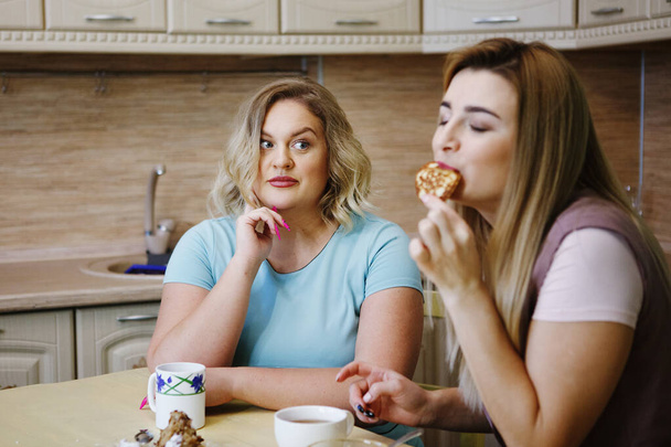 キッチンで 2 つのガール フレンド女性が楽しい時を過すそして食糧を食べる. - 写真・画像