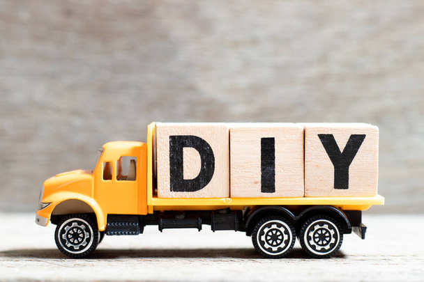 Вантажівка тримає блок літер у слові DIY (скорочення зробити це самостійно) на фоні дерева
 - Фото, зображення