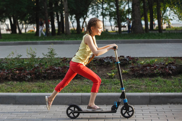 Adolescente criança montando uma scooter em um parque da cidade
. - Foto, Imagem