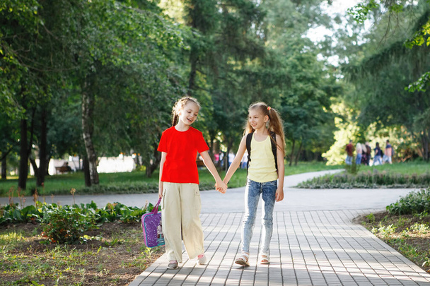 Two teen girls walk along the pavement in the park. - 写真・画像