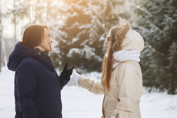 Két fiatal, csinos nő egy havas erdőben. - Fotó, kép