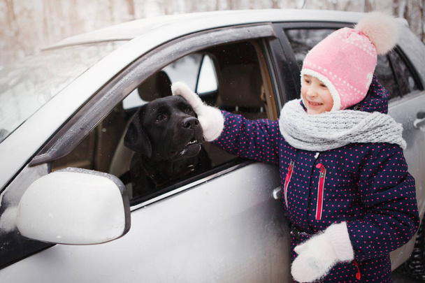 Chica joven con un negro Labrador retriever
. - Foto, imagen