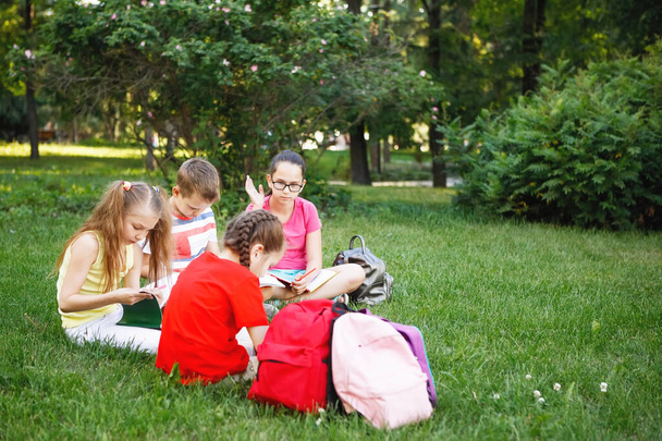 Four children sitting on the green grass. - Fotoğraf, Görsel