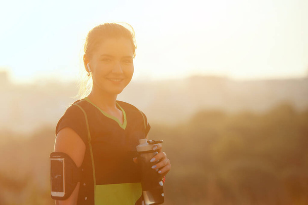 Woman resting after warm-up run with glass in hand - Foto, Imagem