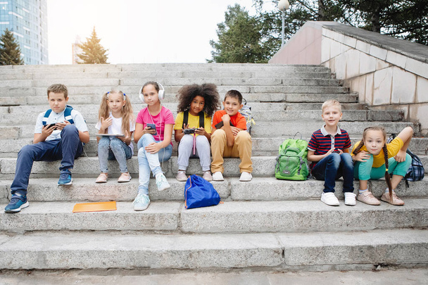Группа школьников, сидящих на ступеньках школы
 - Фото, изображение