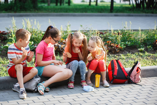 Teenagers sit on the curb in the city park. - Φωτογραφία, εικόνα