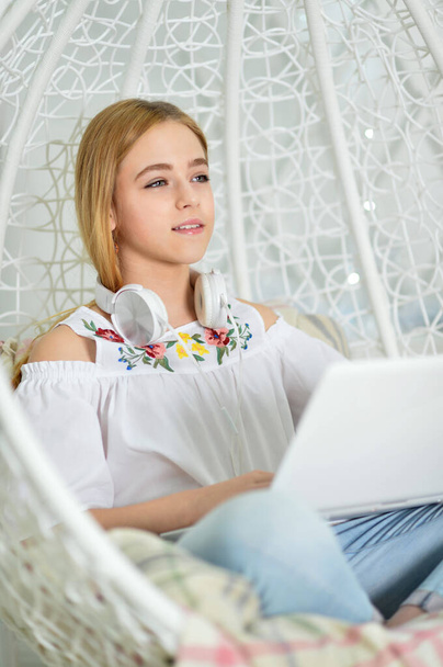 beautiful cute girl using laptop at home on swing - Photo, image