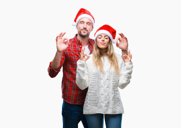 Młoda para w miłości w sobie Boże Narodzenie kapelusz na białym tle relaks i uśmiechnięte oczy zamknięte, robi medytacji gest palcami. Joga koncepcja. - Zdjęcie, obraz
