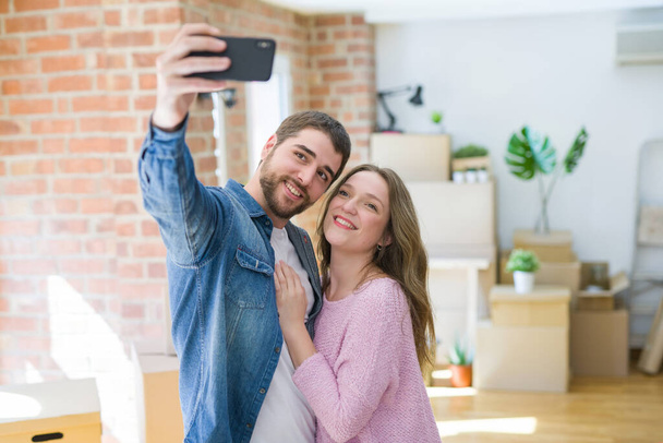 Yeni bir eve taşımak için çok mutlu gülümseyen Smartphone kullanarak bir selfie fotoğraf çekerken genç güzel çift - Fotoğraf, Görsel