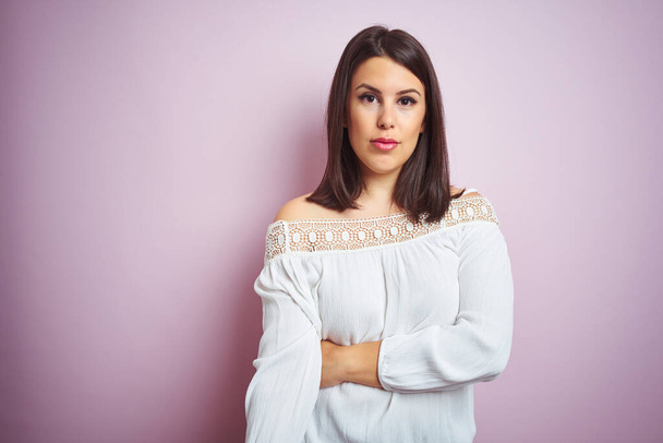 Young beautiful brunette woman over pink isolated background with serious expression on face. Simple and natural looking at the camera. - Фото, зображення