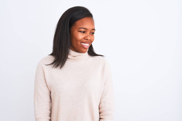 Beautiful young african american woman wearing turtleneck sweater over isolated background looking away to side with smile on face, natural expression. Laughing confident. - Foto, afbeelding