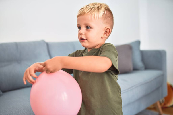 Νεαρό καυκάσιο παιδί παίζει στο νηπιαγωγείο με ροζ μπαλόνι. Παιδί του νηπιαγωγείου χαρούμενο στο playroom με παιχνίδια - Φωτογραφία, εικόνα