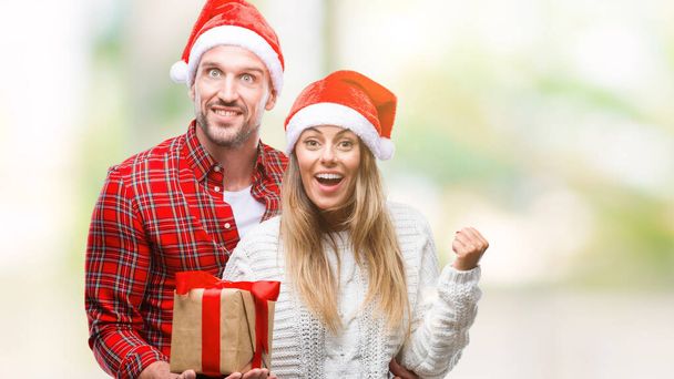 Fiatal pár a szerelem karácsonyi kalapot visel, és a gazdaság jelenlegi át elszigetelt háttérben sikoltozik büszke, és ünnepeljük a győzelem és a siker nagyon izgatott, ujjongott érzelem - Fotó, kép