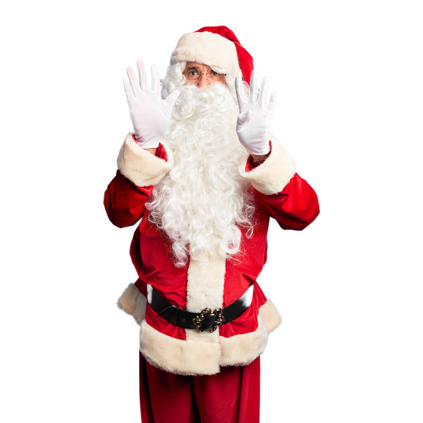 Średniego wieku przystojny mężczyzna w kostiumie Świętego Mikołaja i brodzie stoi pokazując i wskazując palcami numer dziewięć, uśmiechając się pewny siebie i szczęśliwy. - Zdjęcie, obraz