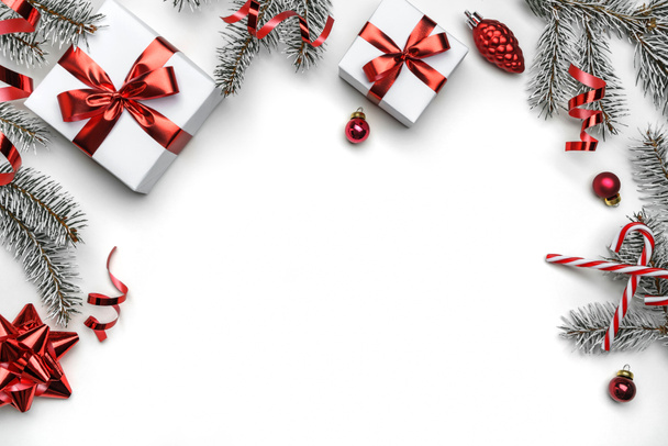 Cornice creativa fatta di rami di abete natalizio, scatole regalo, decorazione rossa, scintille e coriandoli su sfondo bianco. Natale e Capodanno vacanza, bokeh, luce. Posa piatta, vista dall'alto - Foto, immagini