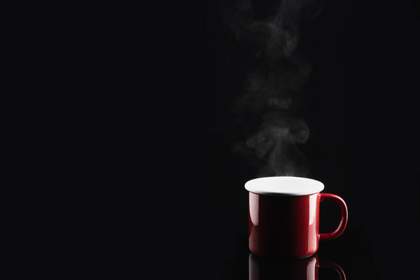 dampfender Kaffee oder Tee in roter Tasse mit Reflexion auf dunklem Backgr - Foto, Bild