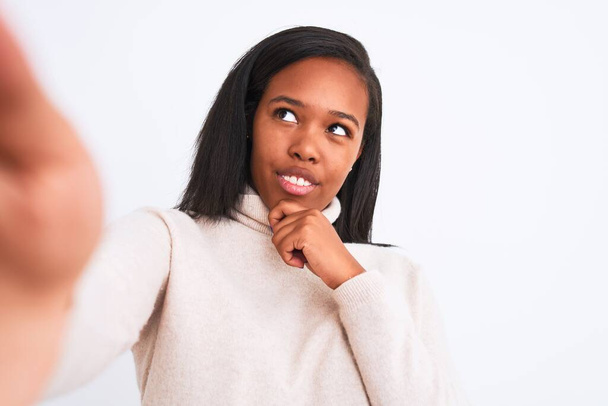 Belle jeune femme afro-américaine portant un pull à col roulé prenant un selfie visage sérieux en pensant à la question, idée très confuse
 - Photo, image