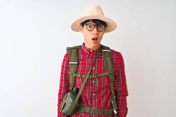 Čínský turista muž na sobě batoh kantýny brýle klobouk přes izolované bílé pozadí strach a šokován překvapením výraz, strach a vzrušený obličej. - Fotografie, Obrázek