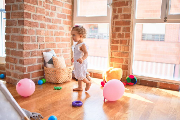 Renkli oyun odasında beyaz güzel bir bebek oyuncaklarla oynuyor. Anaokulunda mutlu ve şen şakrak. - Fotoğraf, Görsel