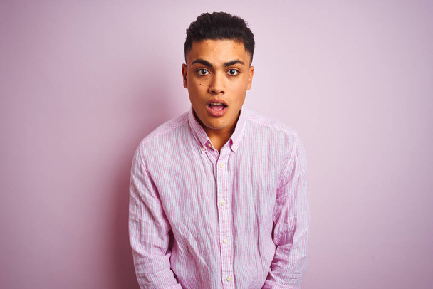 Young brazilian man wearing shirt standing over isolated pink background afraid and shocked with surprise expression, fear and excited face. - Foto, immagini
