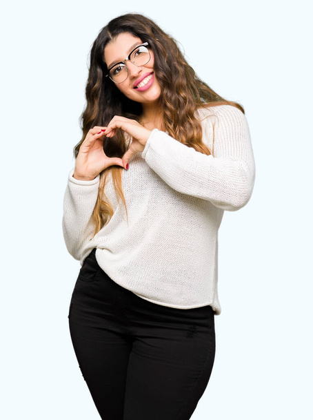 Young beautiful woman wearing glasses smiling in love showing heart symbol and shape with hands. Romantic concept. - Photo, Image