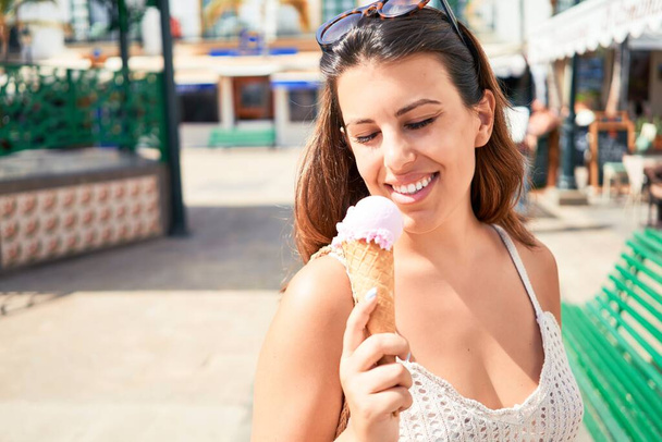 Nuori kaunis nainen syö jäätelöä kartio aurinkoisena kesäpäivänä lomilla
 - Valokuva, kuva
