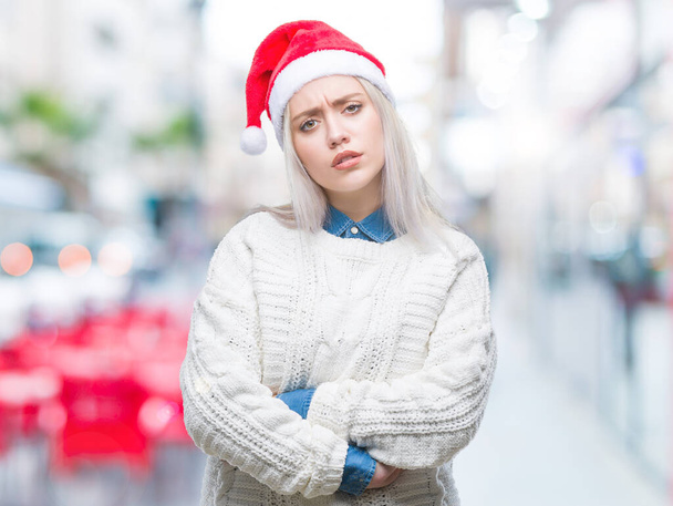 Молода блондинка в різдвяному капелюсі над ізольованим фоном скептично і нервово, не схвалюючи вираження на обличчі схрещеними руками. Негативна людина
. - Фото, зображення