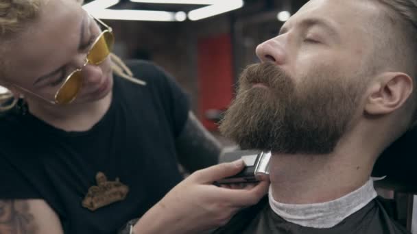Young handsome bearded man at barbershop, shallow depth of field - Materiał filmowy, wideo