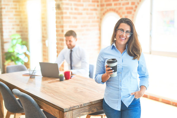 Nuori liiketiimi työskentelee toimistossa, pääkonttori nainen seisoo smilig positiivinen juominen kuppi kahvia
 - Valokuva, kuva